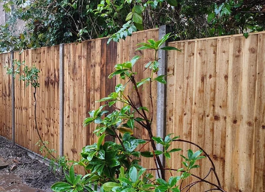 New close-board fence on concrete posts and gravel boards down the side of a house