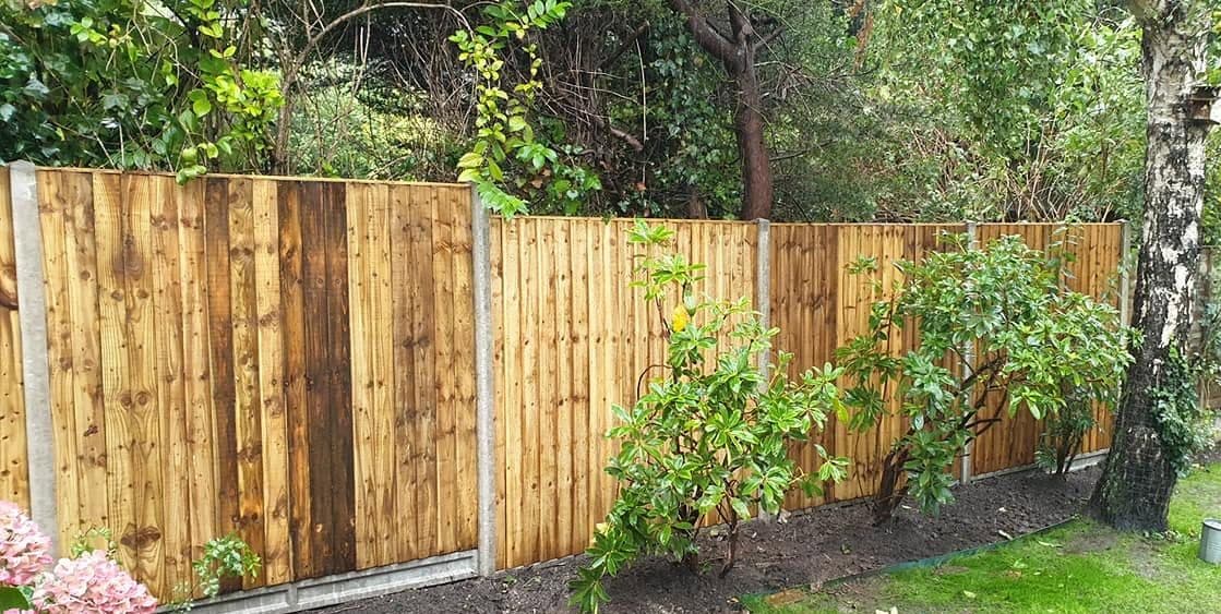New close-board fence on concrete posts along a garden boundary, border dug over in front