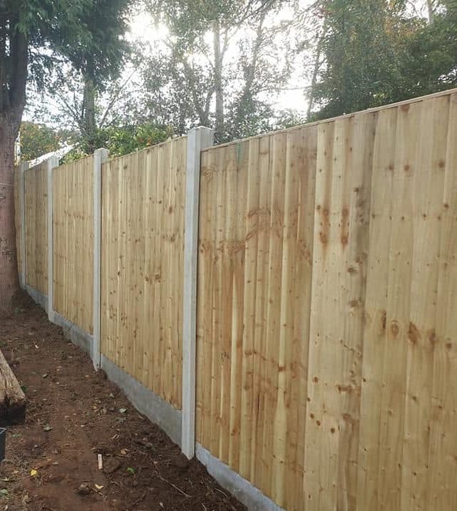 New closeboard fence on concrete posts and gravel boards running down a garden side boundary