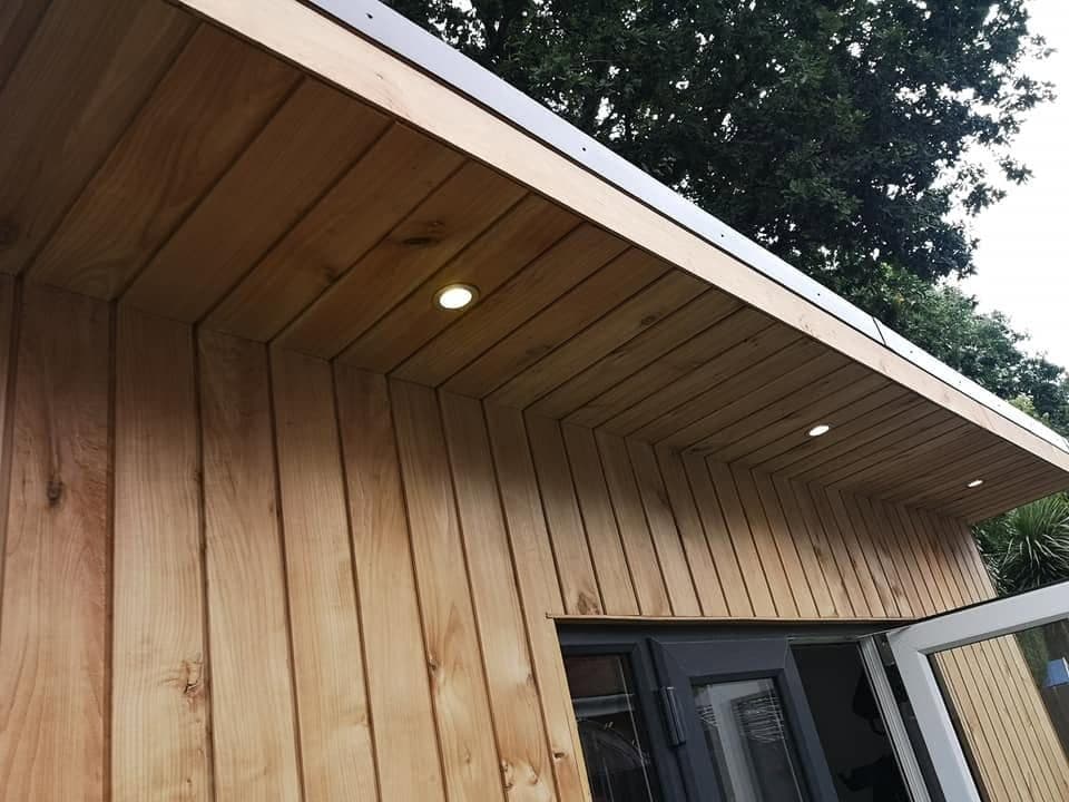 Underside of a timber garden room roof overhang, clad in vertical boards with three LED downlights