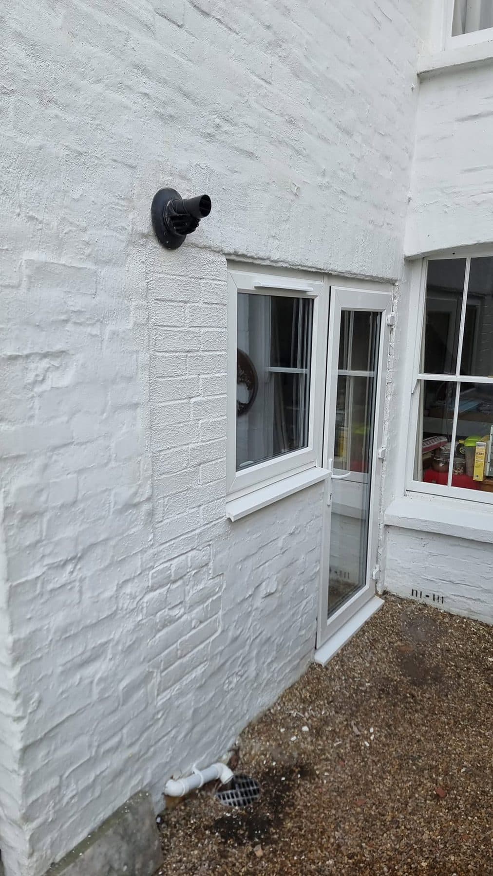New white uPVC window and back door in a painted brick wall, opening made good
