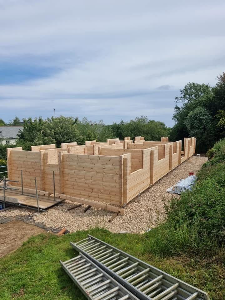 Log building walls part built on a gravel pad, interlocking corners and internal walls set out