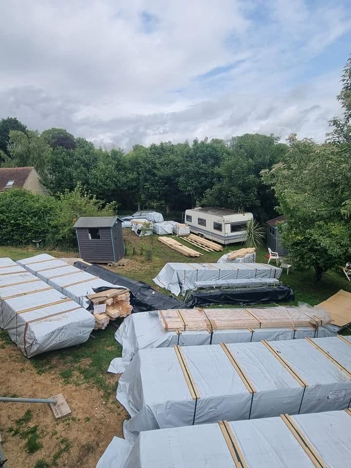 Timber packs for a log building delivered and laid out across a garden lawn