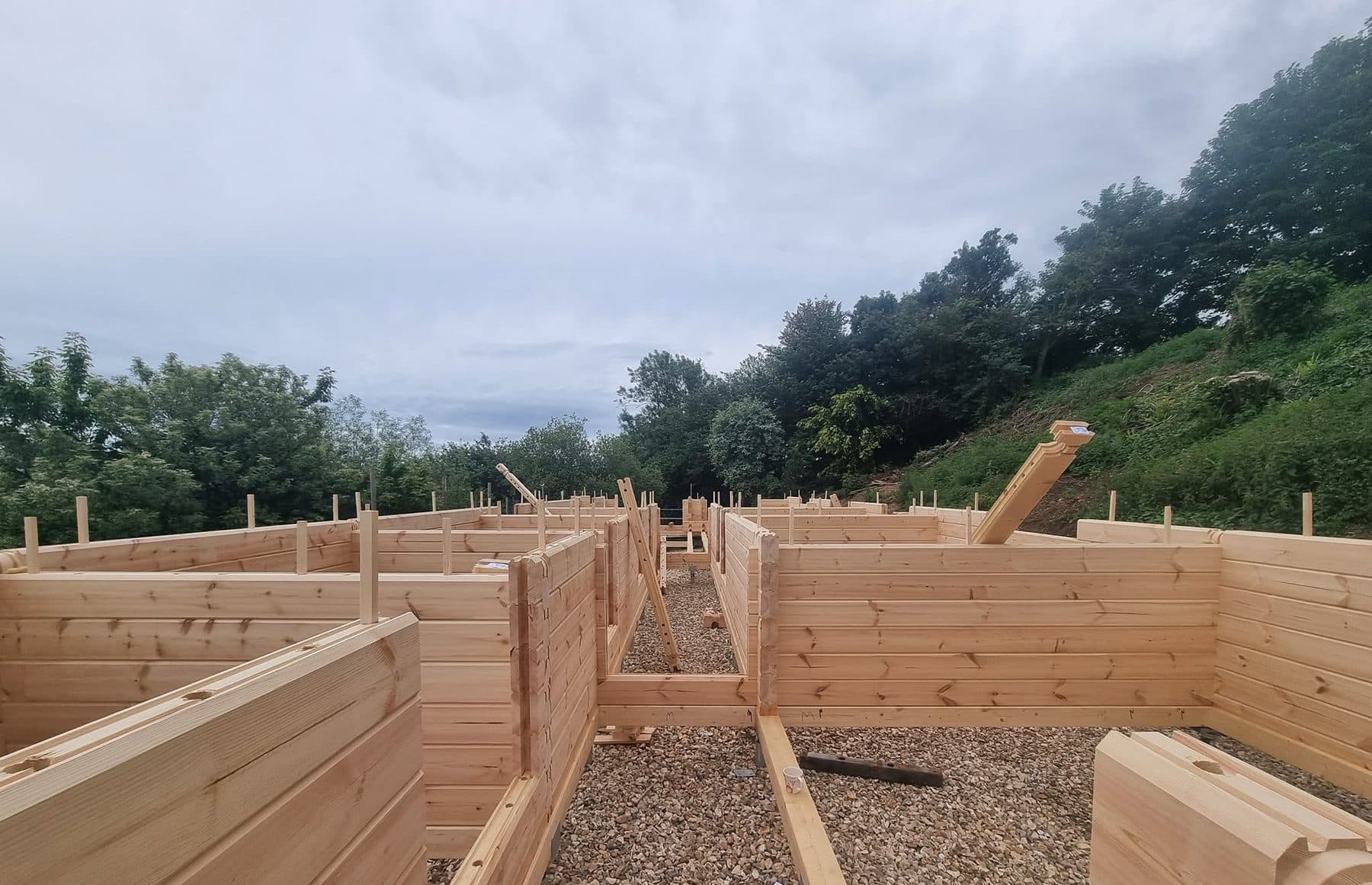 Interlocking log walls part built with dowels standing proud, over a gravel subfloor