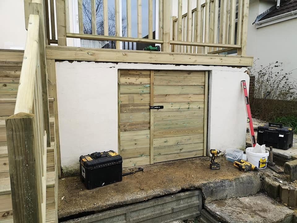 New timber double doors fitted to a store under a raised deck, with treated timber steps and balustrade above