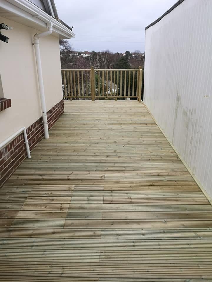Finished raised timber deck walkway along the side of a house, ending at a spindle balustrade