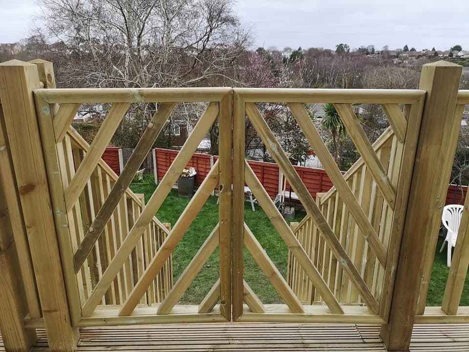 Pair of treated timber deck gates with diagonal braced panels at the top of steps, lawn below