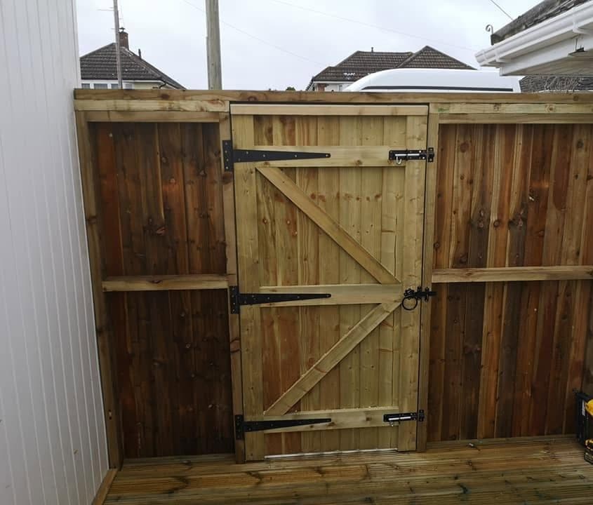 Close-boarded timber fence with a ledged and braced gate on black T-hinges, at the end of a raised deck