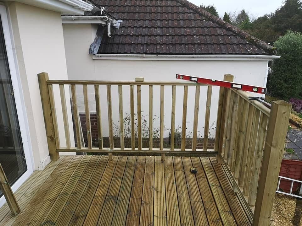 Timber balustrade going up on a raised deck, with a spirit level resting on the handrail