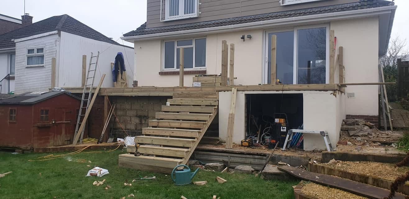 Raised timber deck frame under construction at the back of a house, with new timber steps up to it