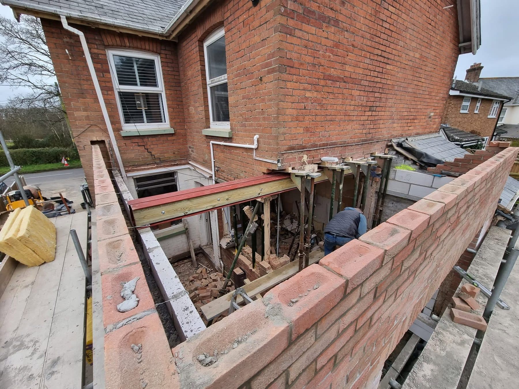 New brick extension walls with a steel beam and props supporting the existing house wall during structural works