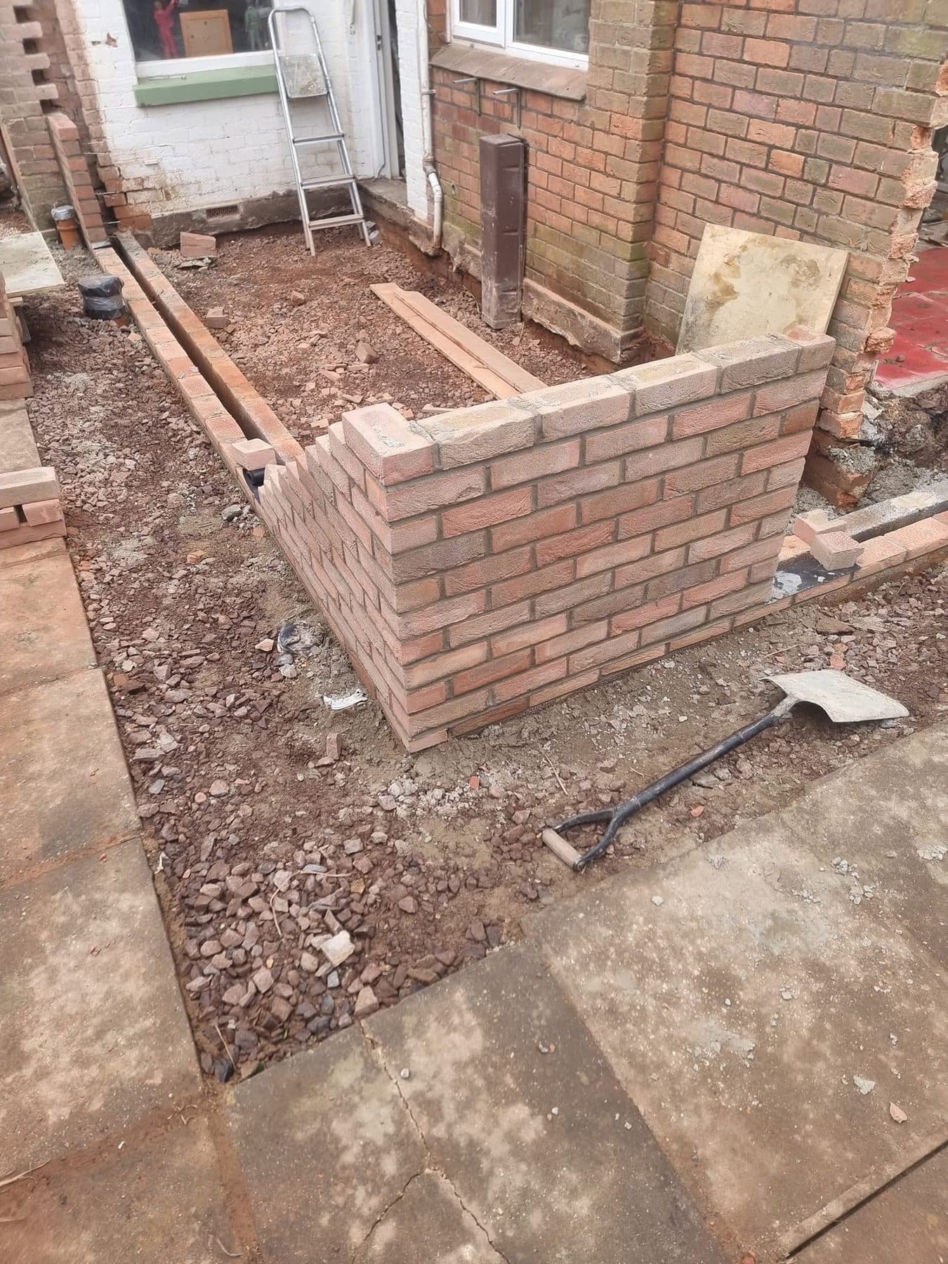 First courses of red facing brick on new extension footings, with hardcore fill inside the footprint