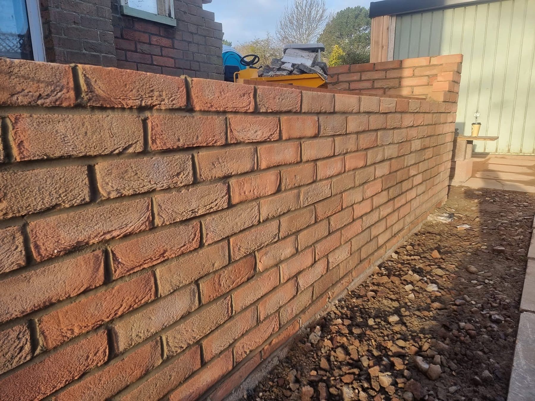 Close view of new red facing brickwork on an extension wall, with neat joints along its full run