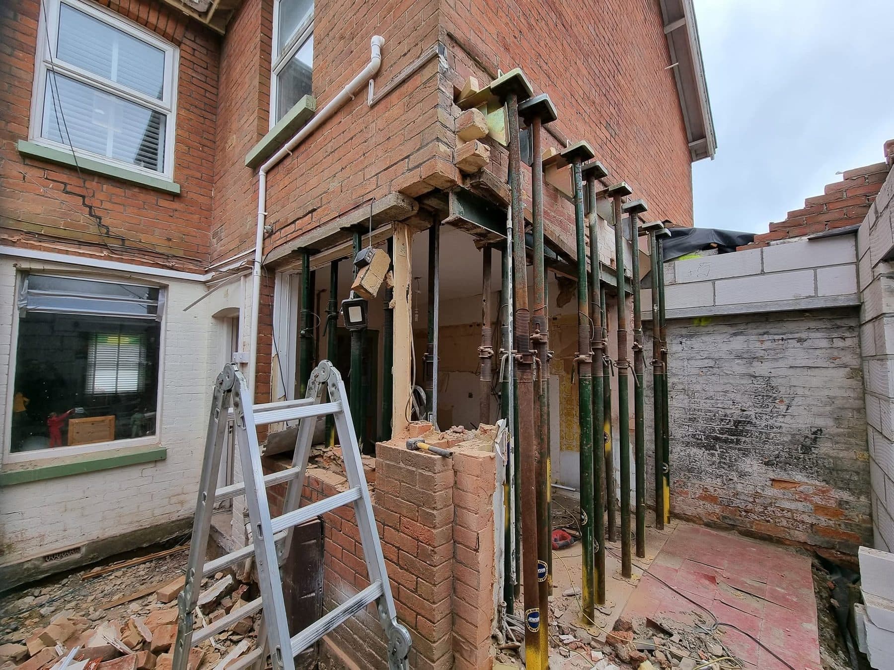 Rear house wall supported on rows of steel props while a wide opening is formed below it