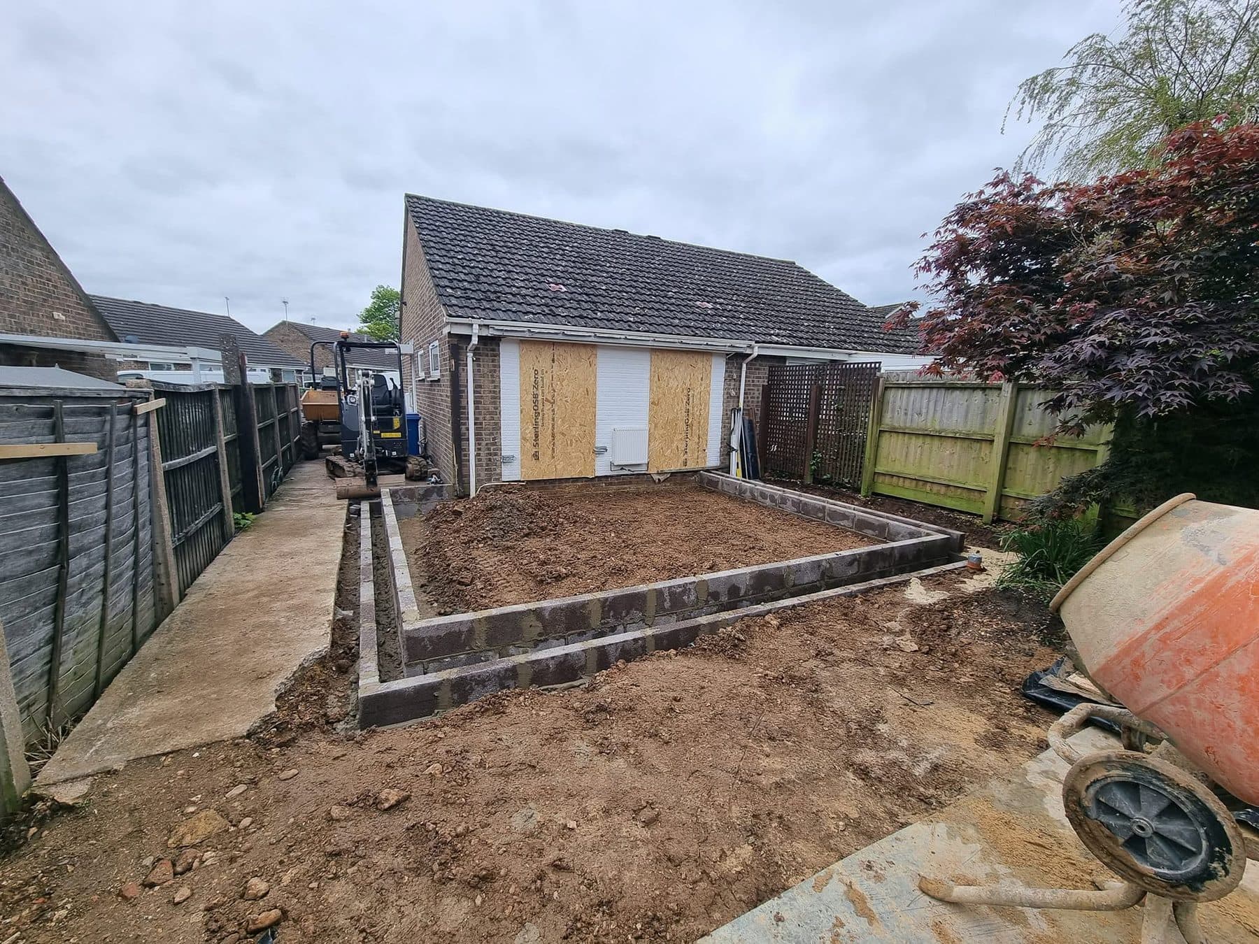 Blockwork foundation walls for a rear extension to a bungalow, mini excavator and mixer on site