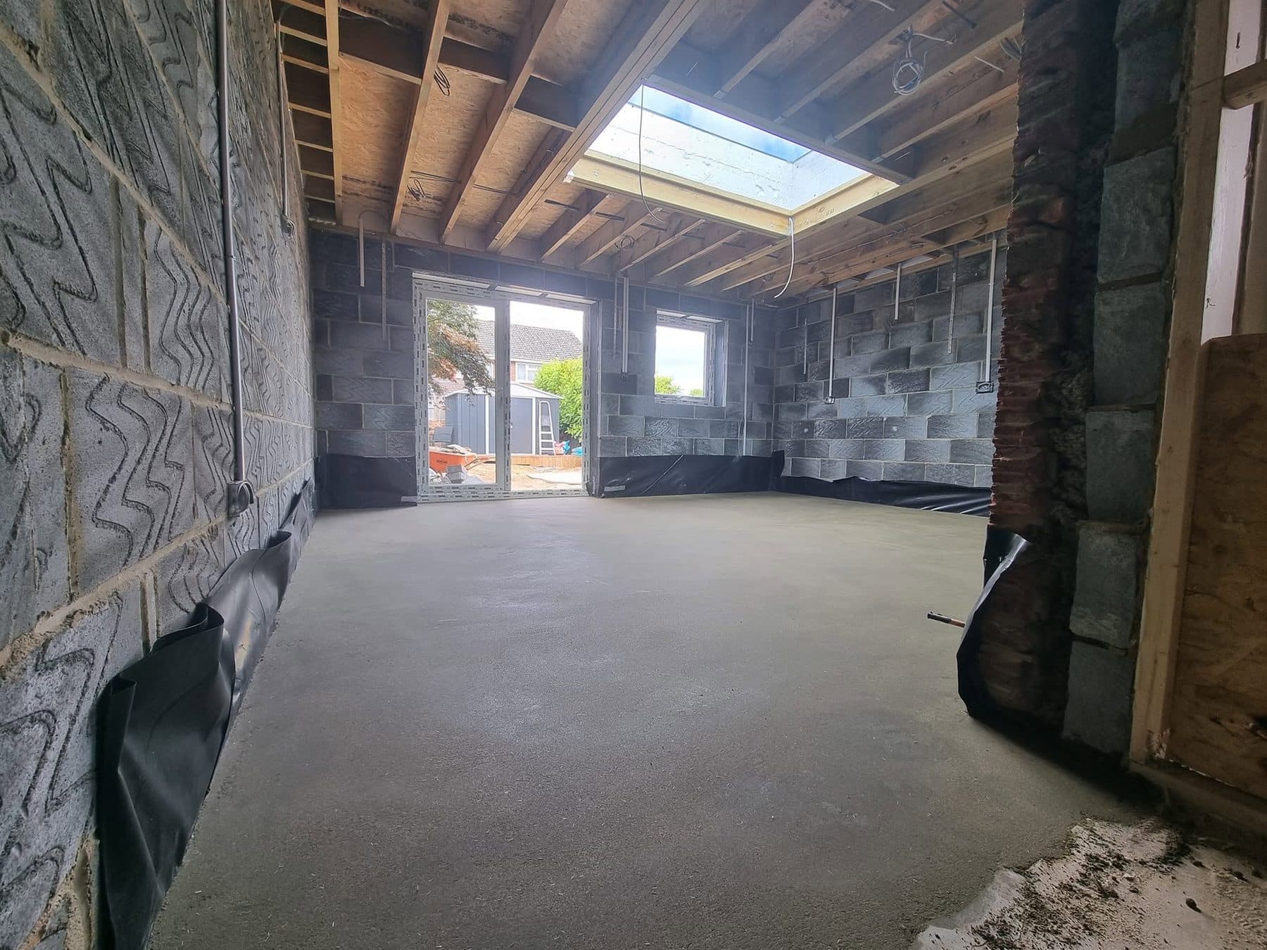 Extension interior with new concrete floor, blockwork walls, roof joists, rooflight and French doors fitted