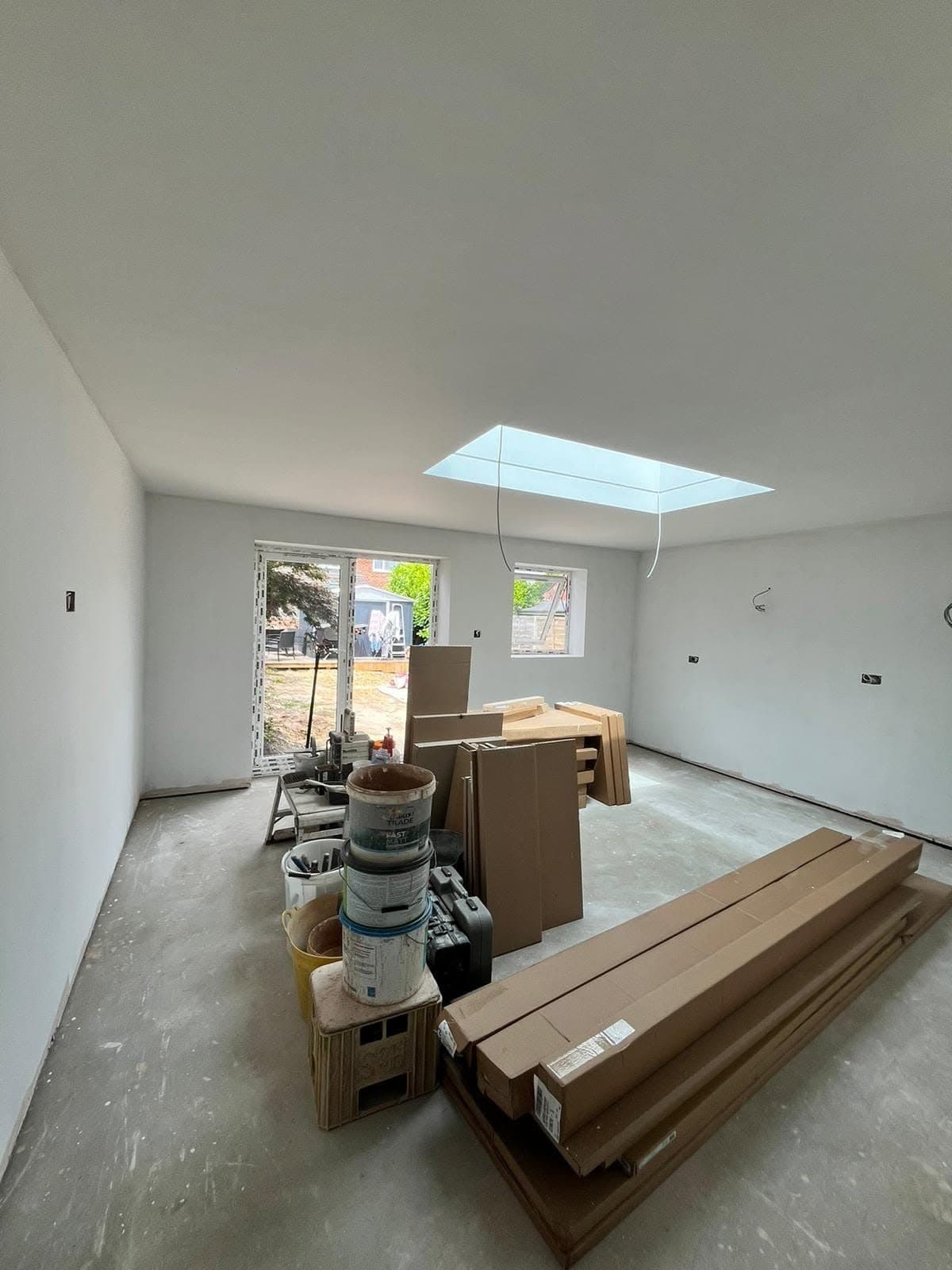 Plastered extension with rooflight and French doors, kitchen units boxed up on the floor ready to fit