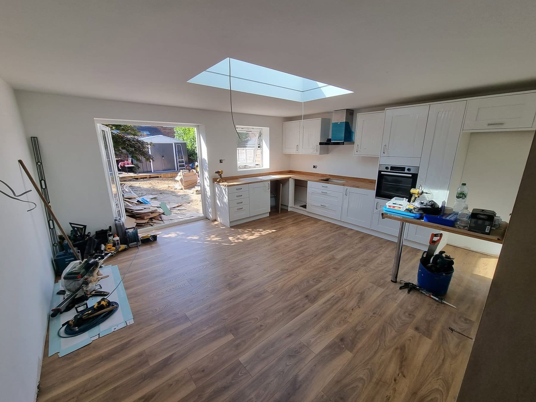 Kitchen extension with white shaker units, wood worktops, wood-effect floor, rooflight and French doors