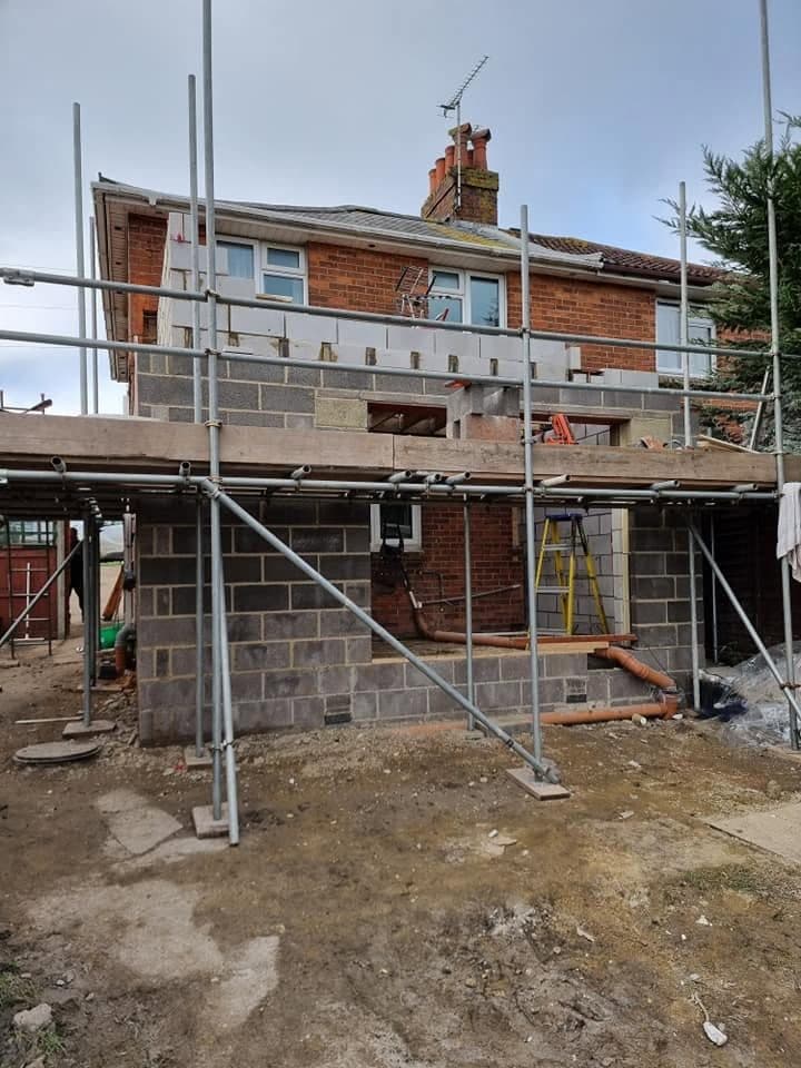 Ground-floor blockwork of a two-storey rear extension, with first-floor walls starting and scaffold around
