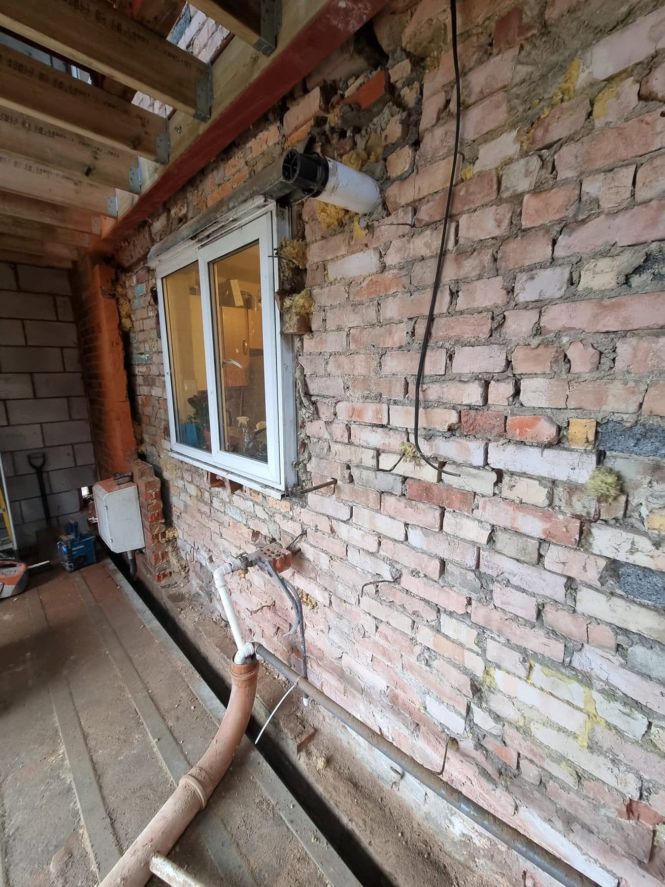 Existing rear brick wall exposed inside the extension, with new floor joists and steel above