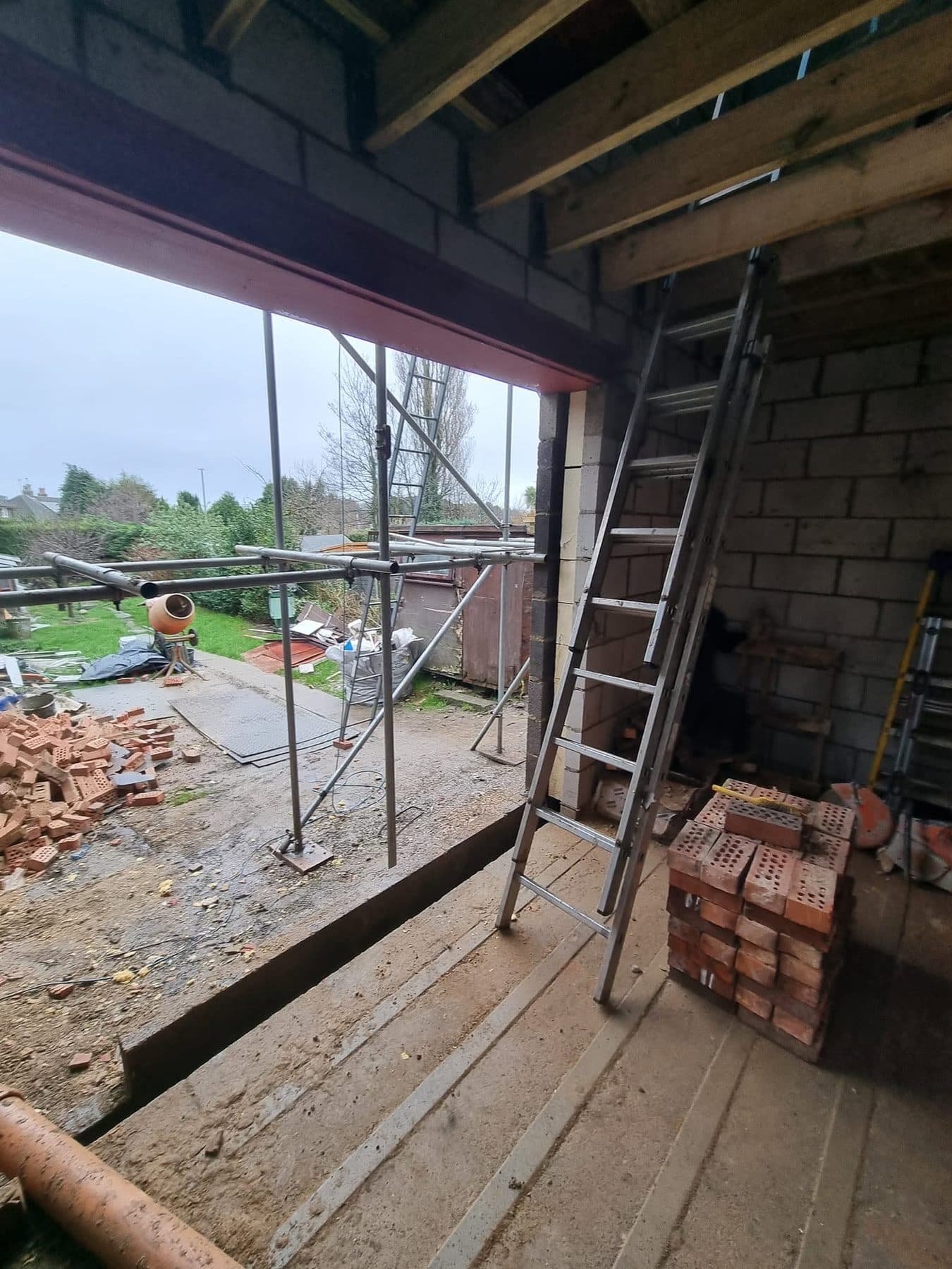 Wide opening with a steel beam over, looking out from inside the extension to the garden