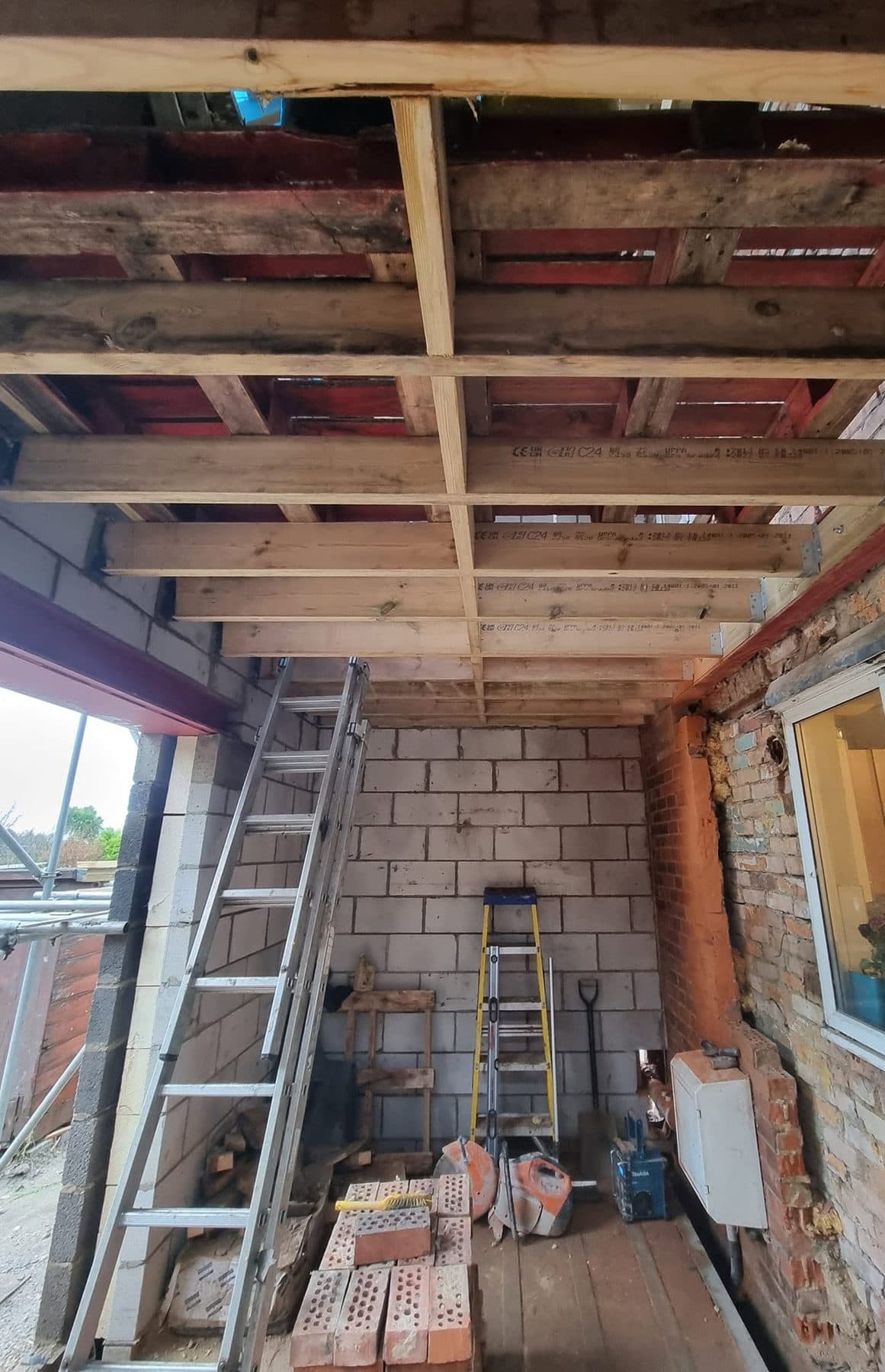 New first-floor joists on hangers with painted steel beams, inside a rear extension