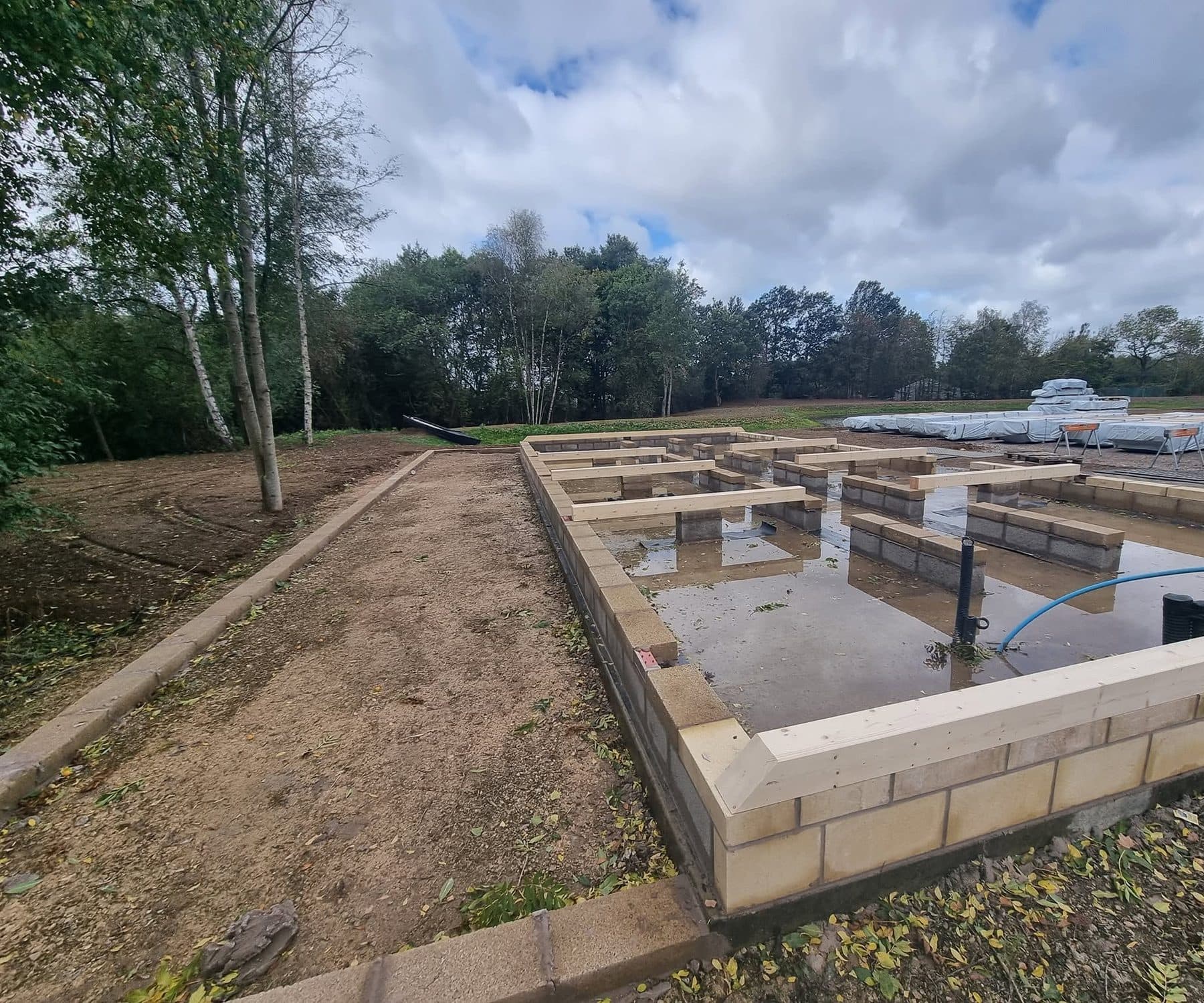 Blockwork base with timber wall plate and incoming water pipe, block-edged path base alongside
