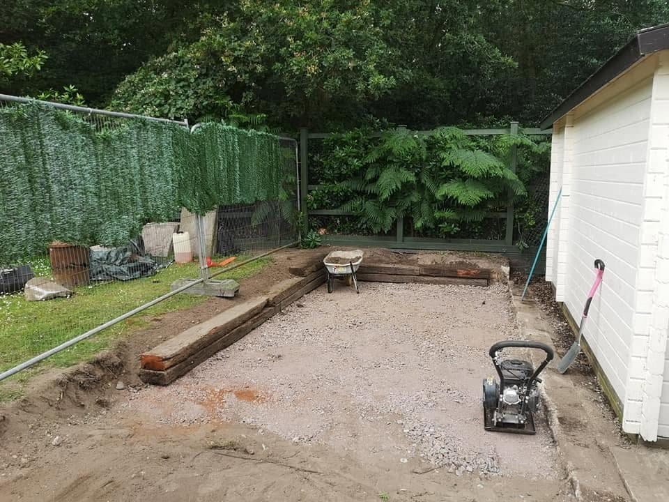 Dug-out garden base with compacted stone sub-base and a sleeper retaining edge, plate compactor on site